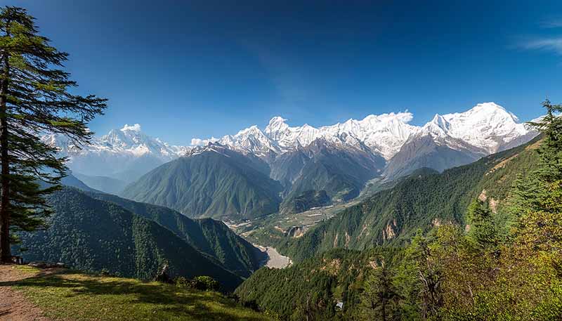 A wide-angle shot of the Himalayan range with lush valleys below, taken from the guest house